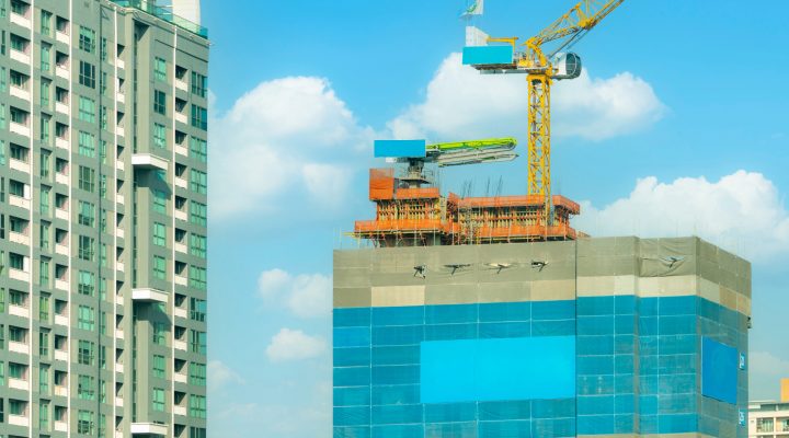 Construction site with crane and skyscraper building. Real estate industry. Crane in construction site. Project development in real estate company concept. Construction crane work against blue sky.